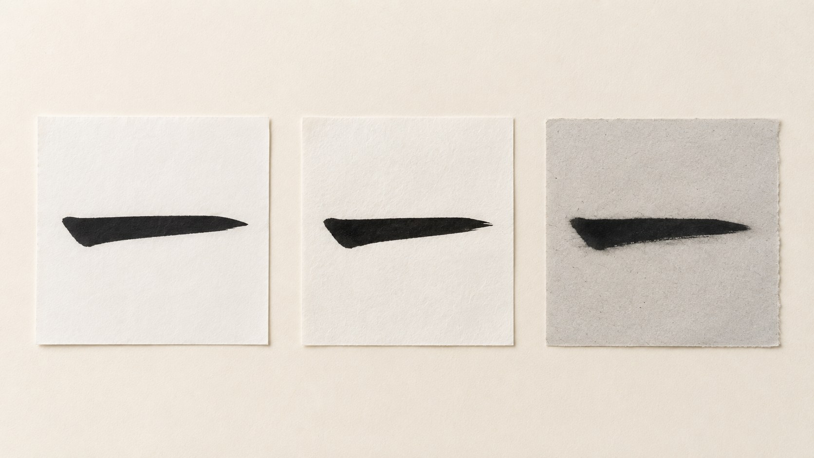 Three squares of Japanese calligraphy practice paper in a row, each with the same test brushstroke of the kanji 一, showing how bulk hanshi, branded hanshi, and newsprint each take the ink differently.
